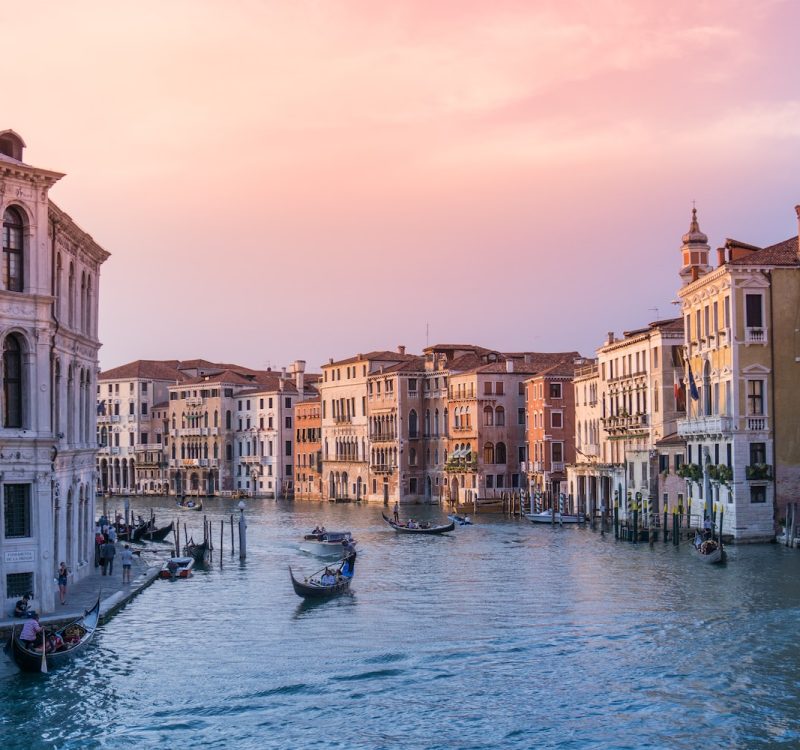 photo of gondolas on body of water between buildings